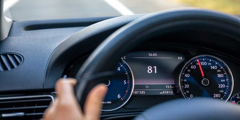 A driver holding the steering wheel while looking at the digital speedometer and tachometer display to measure engine performance.